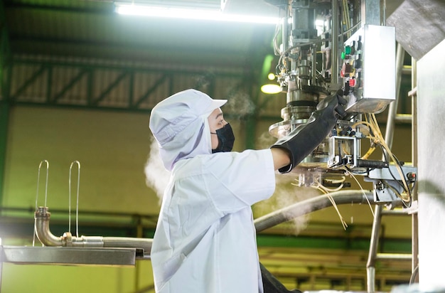 Female worker in a ketchup factory Controlled automatic aseptic filling machine filling ketchup into large vats at an industrial facility in Asia food industry Agroindustry