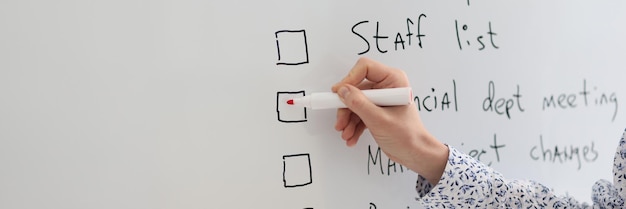 Female worker marks schedule points written on whiteboard in office woman makes to do list to