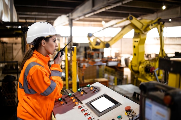 Female worker in safety equipment controlling industrial manufacturing process in factory