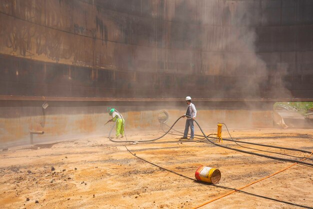 Female worker surface corrosion plate preparation by sand blasting of tank internal oil