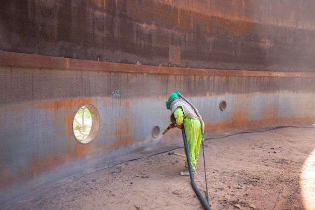 Female worker surface corrosion plate preparation by sand blasting of tank internal oil