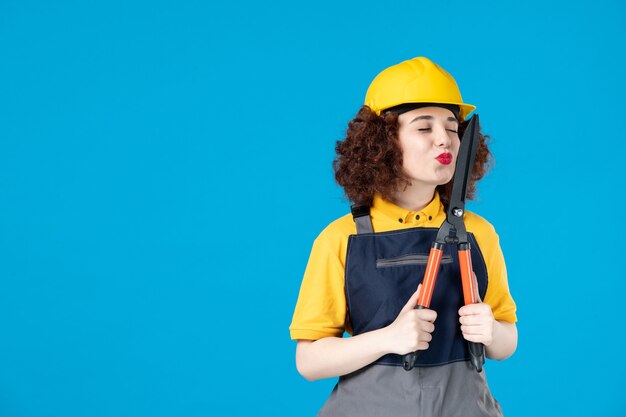 Female worker in uniform with secateurs on blue