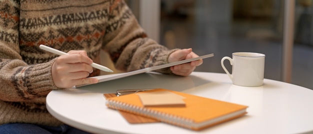 デジタルタブレットとコーヒーテーブルのスケジュール帳で自宅で働く女性労働者