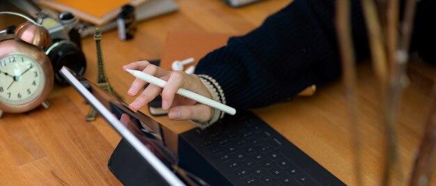 Foto lavoratrice che lavora con la compressa digitale sulla scrivania di legno con i rifornimenti e le decorazioni