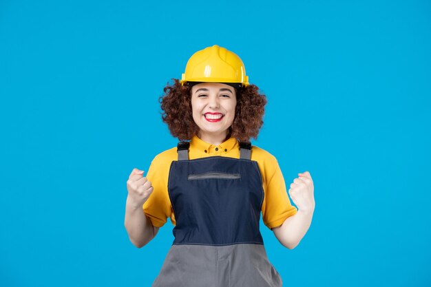 Female worker in yellow uniform and helmet on blue