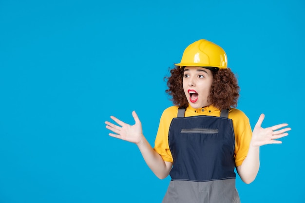 Photo female worker in yellow uniform and helmet on blue