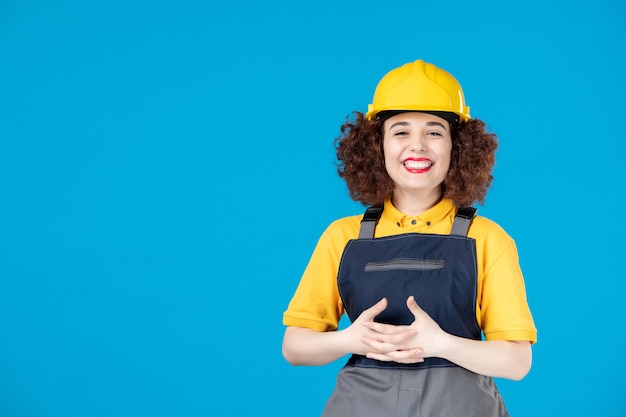 Female worker in yellow uniform and helmet on blue