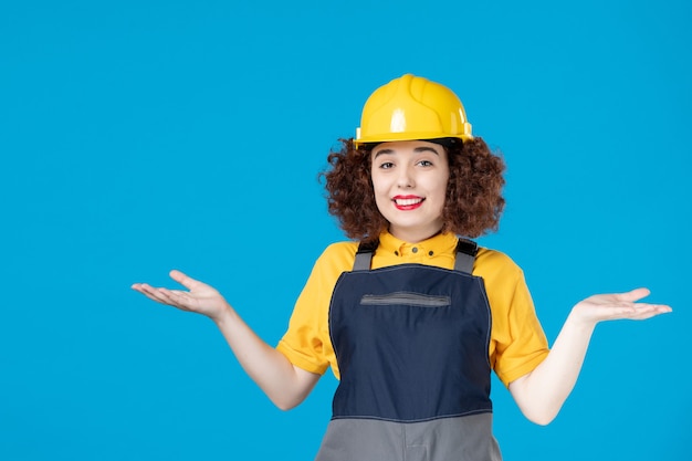 Female worker in yellow uniform and helmet on blue