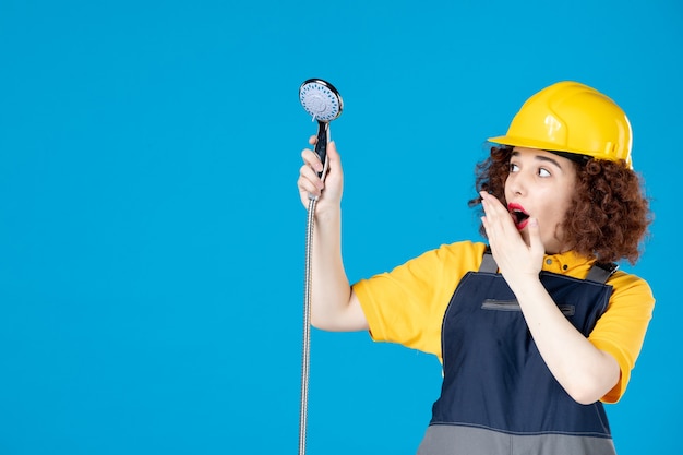 Female worker in yellow uniform holding shower on blue desk