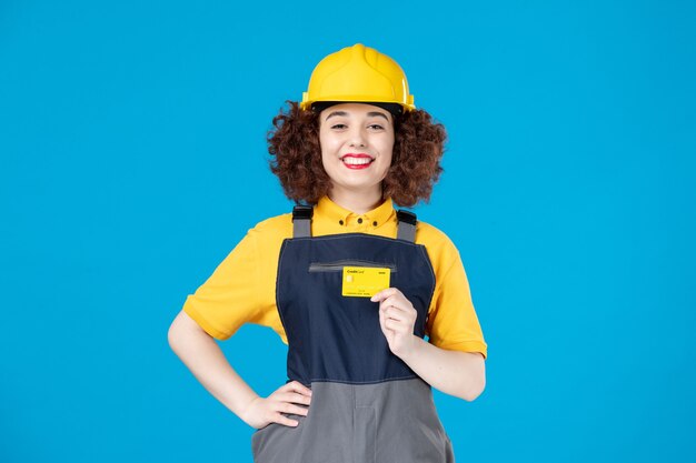 Female worker in yellow uniform with credit card on blue