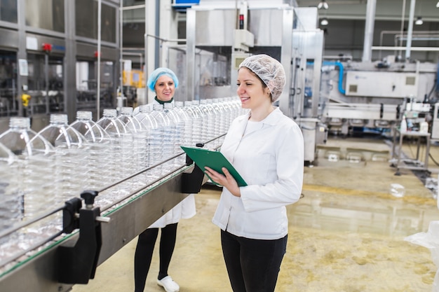 Female workers in bottling factory checking water bottles before shipment