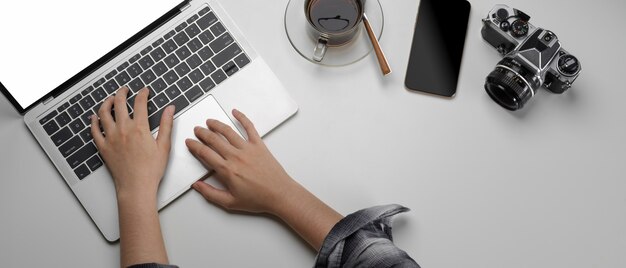 Female working on workspace with mock-up laptop, smartphone and camera