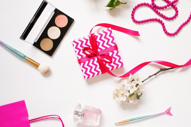 Female workplace of a fashion blogger Cosmetics a gift box with a bow Flat lay on a white background