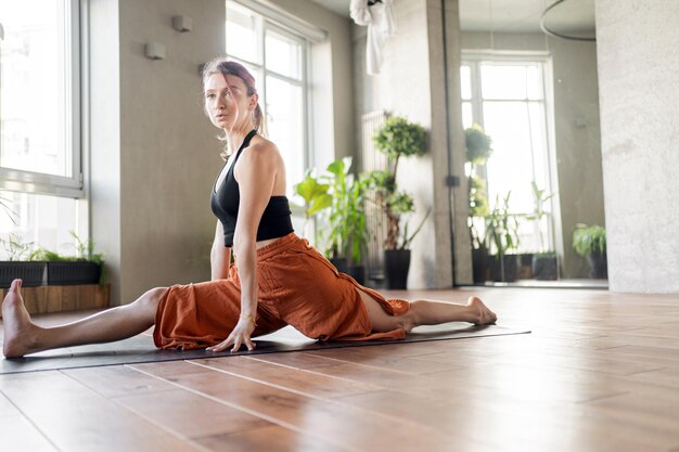 A female yoga instructor trains on a mat in a modern interior fitness club