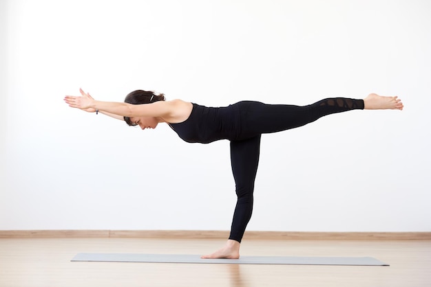 Female yogi standing on one leg Yoga asana Warrior 3 Pose Balance between body and spiritual essence White background