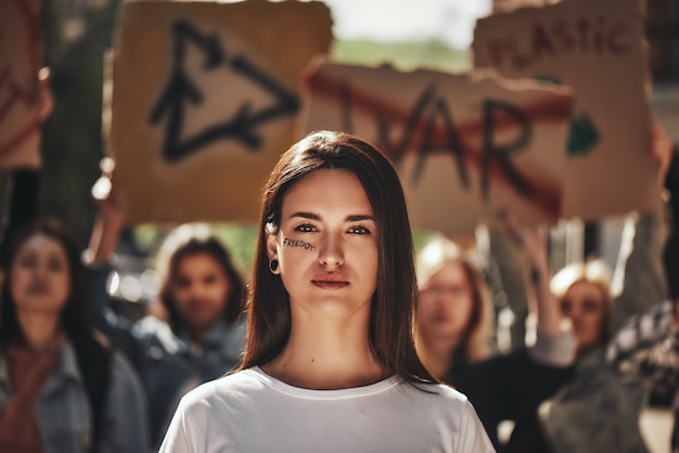 Photo female young activist with word freedom written on her face protesting outdoors