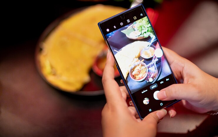 Photo 女性はスマートフォンを持ちソーシャルメディアに展示するためにベトナム料理の写真を撮っています