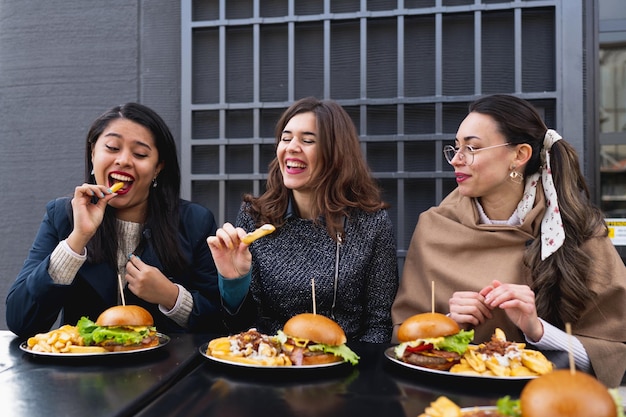 ハンバーガーを食べる女性。一緒に昼食を食べながら笑顔で楽しんで幸せな女性