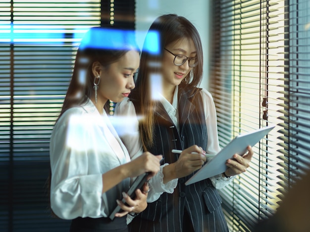 females office workers consulting on their project while standing in office