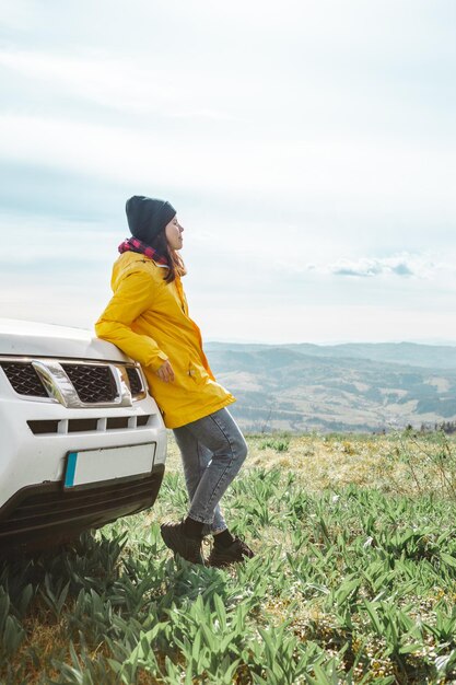 山の頂上でSUVの車の近くに立っている女性