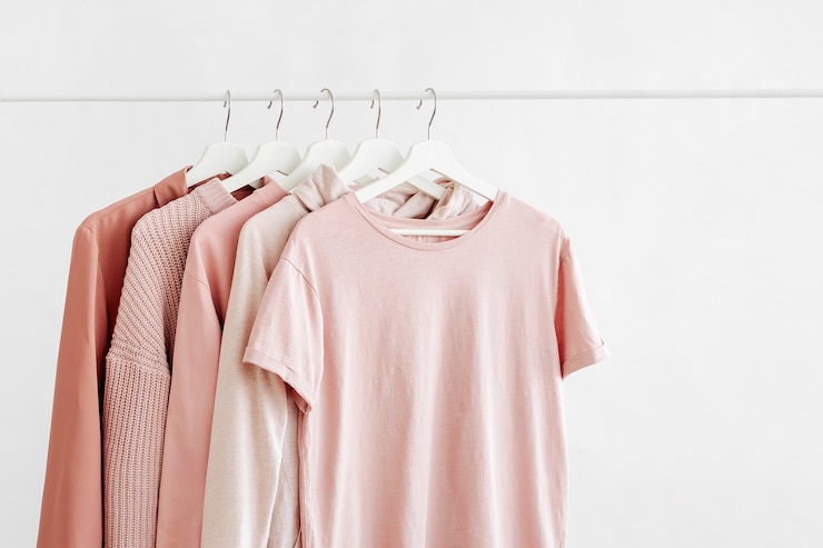 Photo feminine clothes in pastel pink color on hanger on white background. spring cleaning home wardrobe. minimal fashion concept.