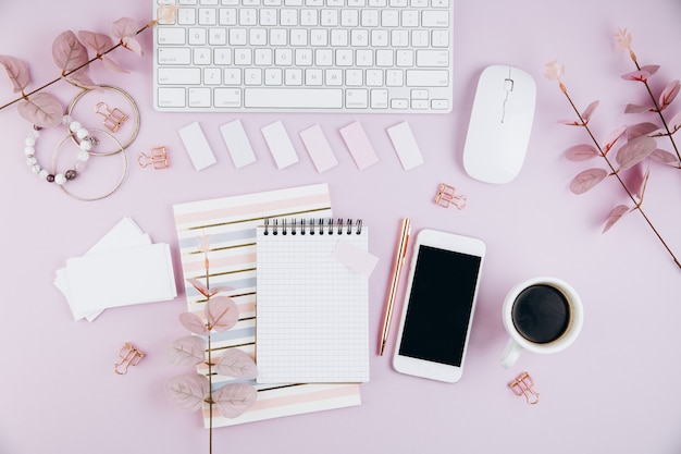 Feminine desk workspace with keyboard, smartphone, golden clips on violet