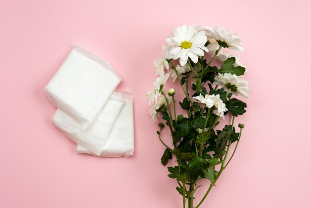 Photo feminine gasket for menstruation and white flower on a pink background