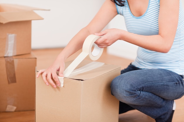 feminine hands taping a box