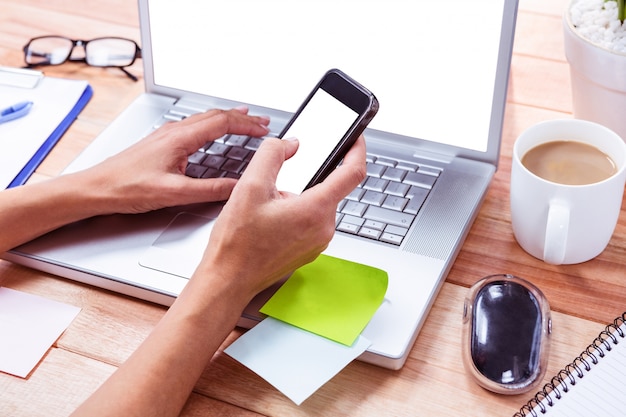 Feminine hands using smartphone and laptop