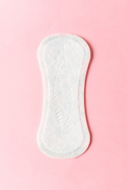 写真 ピンク色の背景に女性用衛生パッド。月経時の婦人衛生の概念