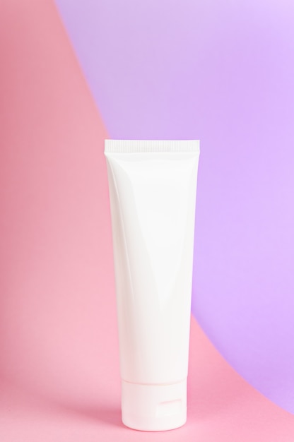 Feminine hygienic product tube on pastel pink and lilac background.