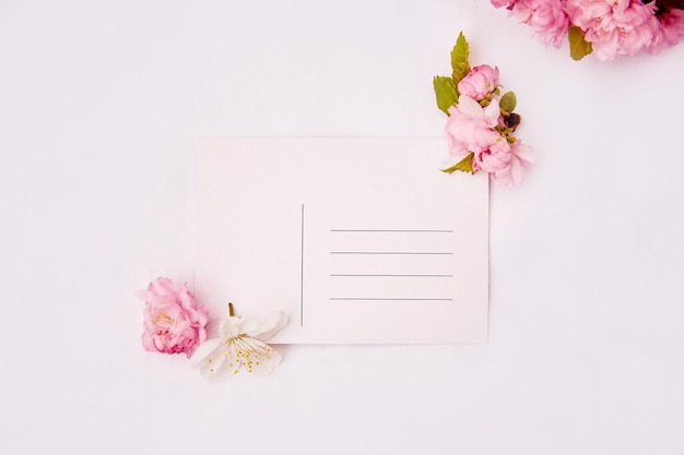 Feminine minimalistic spring pink and white flowers with post card and place for address mock up Invitation romantic wedding birthday mother39s day card concept Copy space Top view