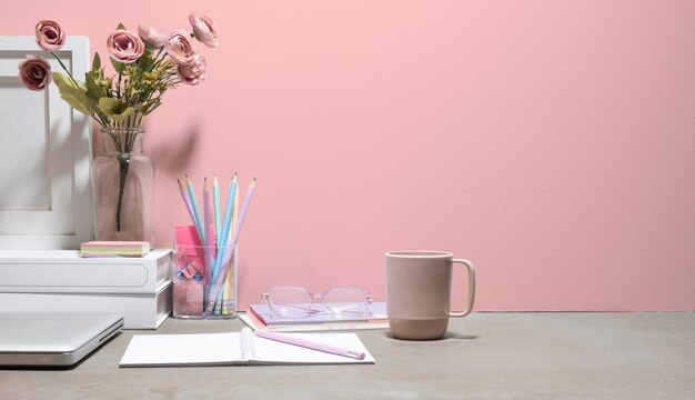 Feminine working desk with coffee cup notepad glasses and pink rose in vase copy space for your text