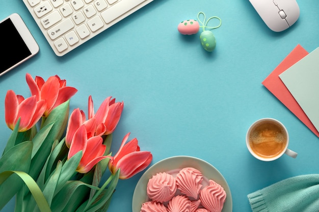 Spazio di lavoro femminile con maglione di cotone, tastiera, telefono cellulare, piatto di marshmallow e tazza di caffè