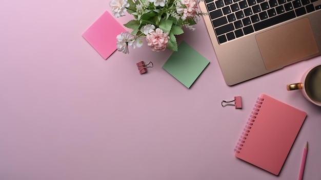 Feminine workplace with laptop computer sticky notes and coffee cup on pink background