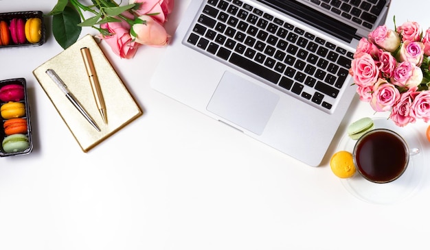 Feminine workspace border with keyboard coffee and flowers top view and copy space on tabletop white background