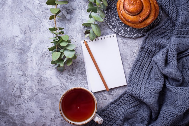 Feminine workspace with bun, cup of tea and notebook