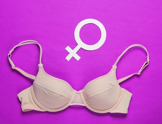 Feminism concept. Female bra, gender symbol on pink background. Top view, minimalism