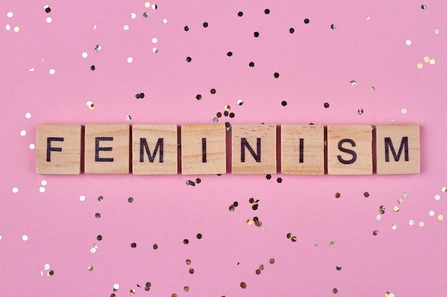 ピンクの背景に木製の立方体に書かれたフェミニズムの言葉
