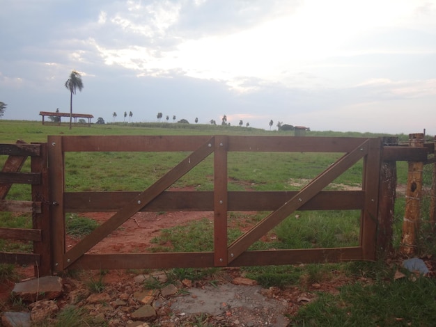 Photo fence on field against cloudy sky