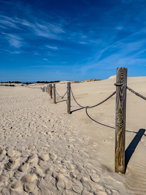 A fence in the sand with a blue sky in the background