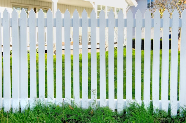 fence of a white wooden garden front view with green grass and part of house background