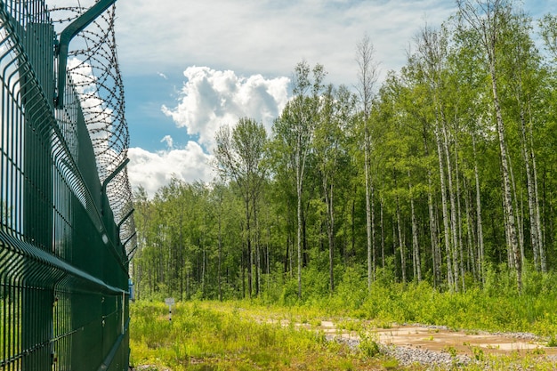 A fence with barbed wire on a blue sky background. Restricted passage area