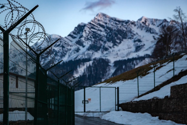 Foto un recinto con un recinto di filo spinato davanti a una montagna innevata.