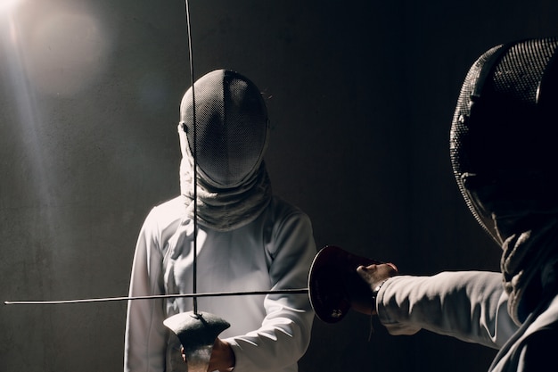 Photo fencer woman with fencing sword. fencers duel concept.