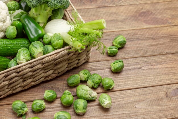 Fennel and Brussels sprouts in a wicker basket. Brussels sprouts on the table. Copy space. Wooden background. Flat lay