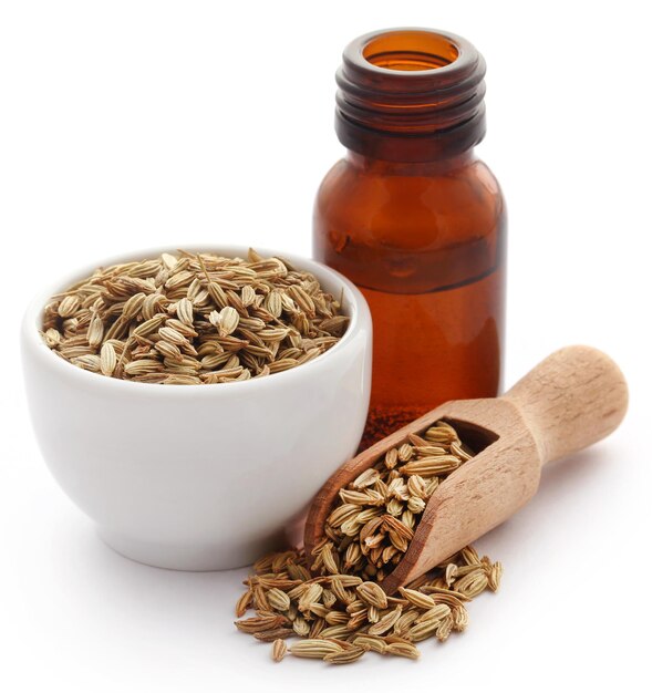 Fennel seeds with essential oil in a bottle over white background