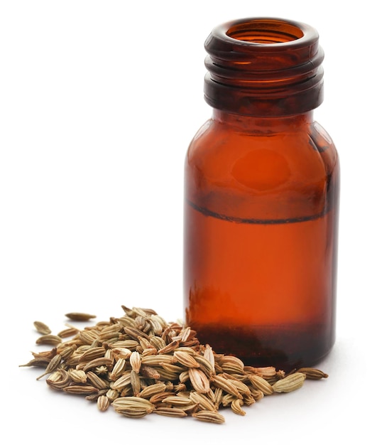 Fennel seeds with essential oil in a bottle over white background