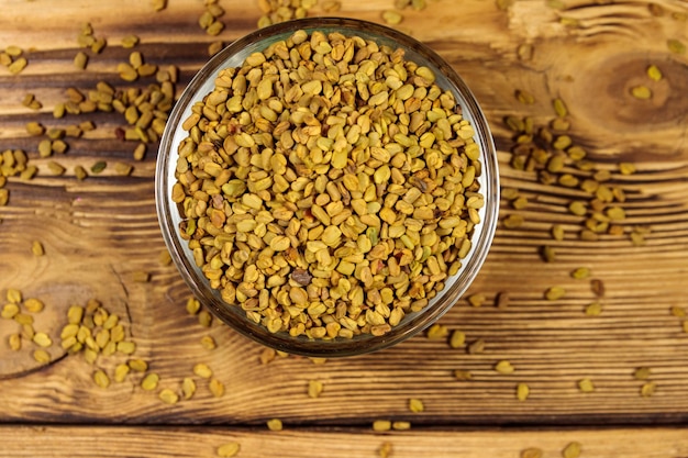 Fenugreek seeds in glass bowl on wooden table