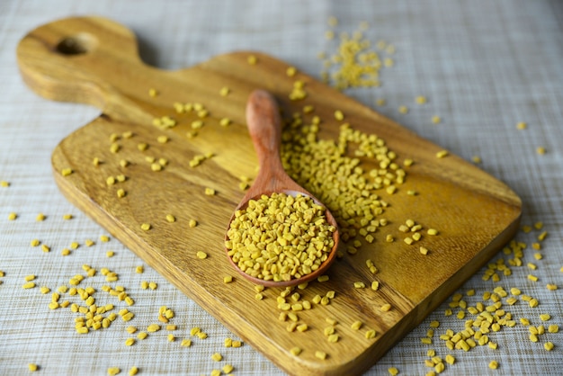 Fenugreek seeds in wooden spoon on textured background